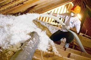 Technician installing blown-in insulation in an attic.