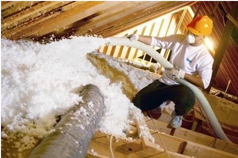 Technician blowing loose-fill insulation into an attic.