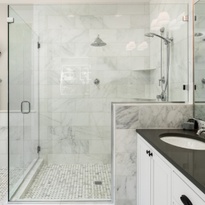 Frameless glass shower door on modern walk-in shower with large white tiles.